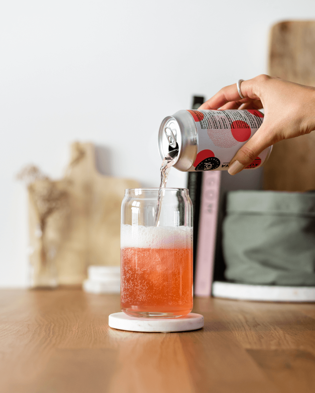 Eine Person gießt Himbeere ROY Kombucha in ein Glas mit Eis.