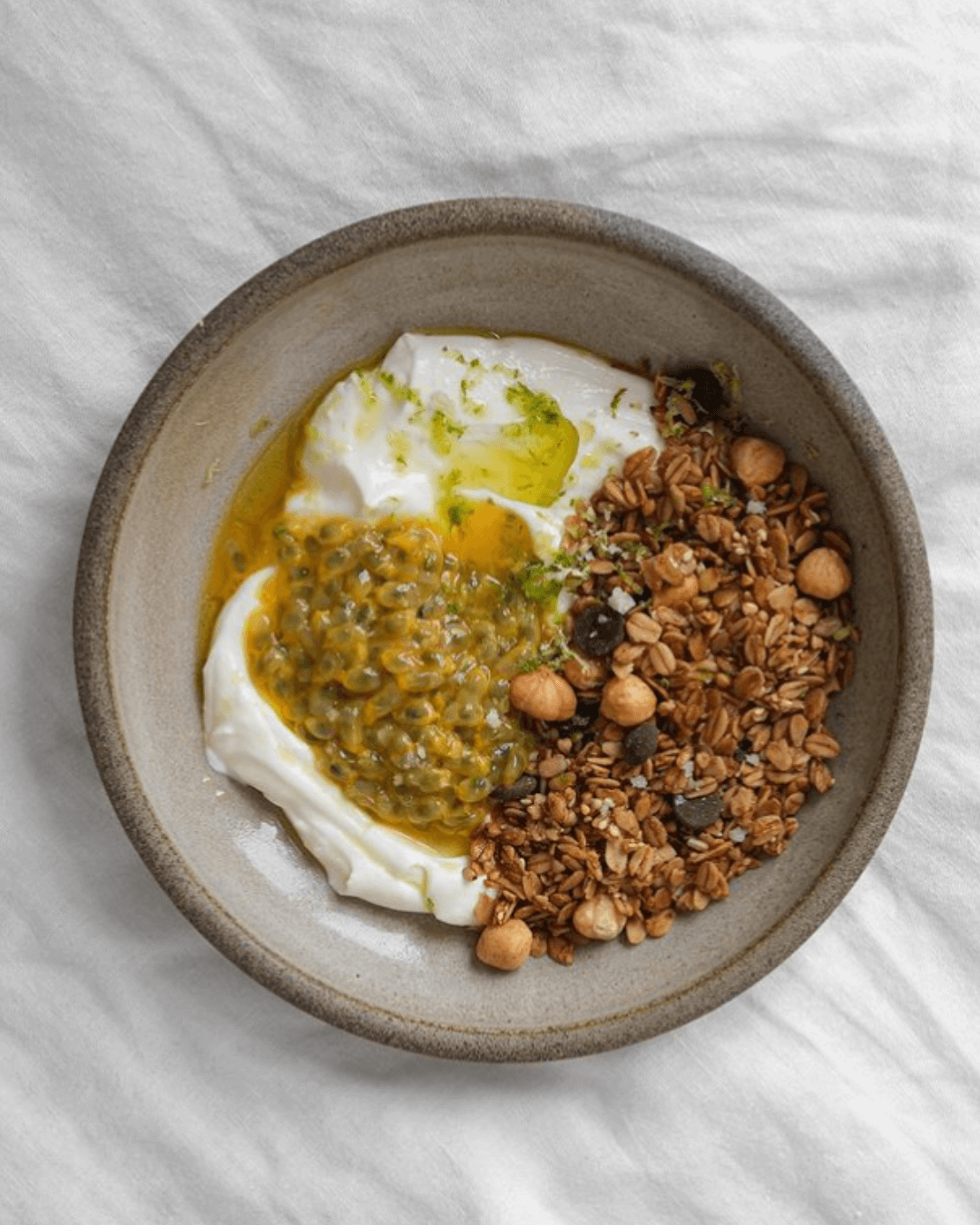 Eine Schale mit Joghurt, Passionsfrucht und Bamboo Breakfast Granola mit dunkler Schokolade und gerösteten Haselnüssen.