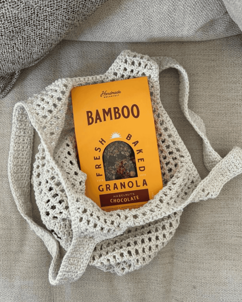Eine Packung Bamboo Breakfast Granola mit dunkler Schokolade und gerösteten Haselnüssen in einer handgemachten Tasche.