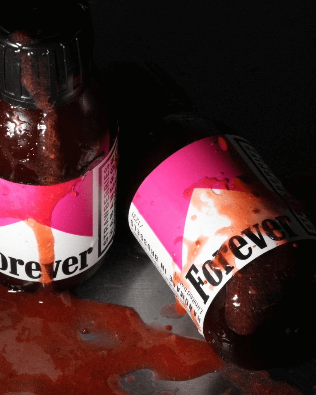 Zwei Flaschen der scharfen Forever Sauce von Swet mit ausgelaufener roter Sauce auf dunklem Untergrund.